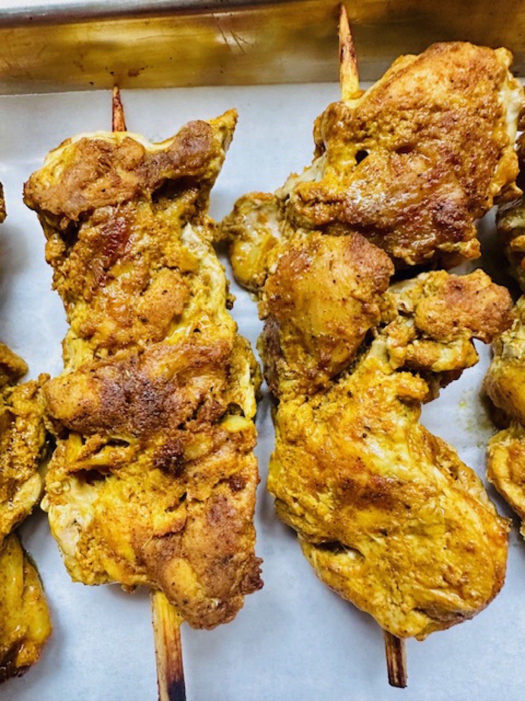 Spiced chicken skewers lined up on the pan, ready for the buffet.
